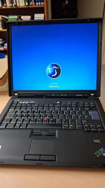 Photo of an old lenovo laptop (with screen open) with lubuntu bootscreen visible.